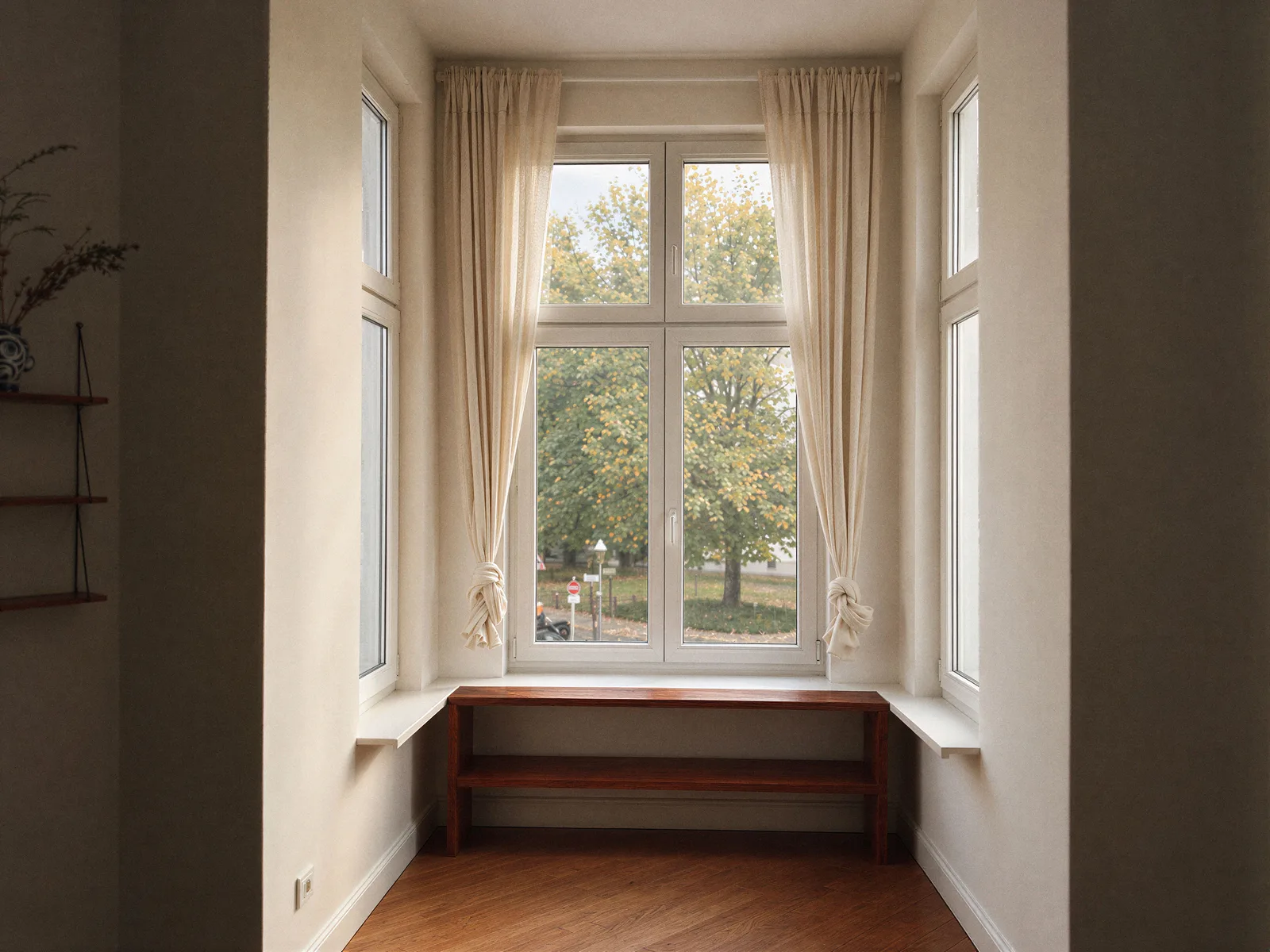 Bay window with white curtains and a view of trees